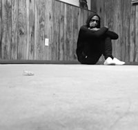 a black and white photo of a man sitting on the floor